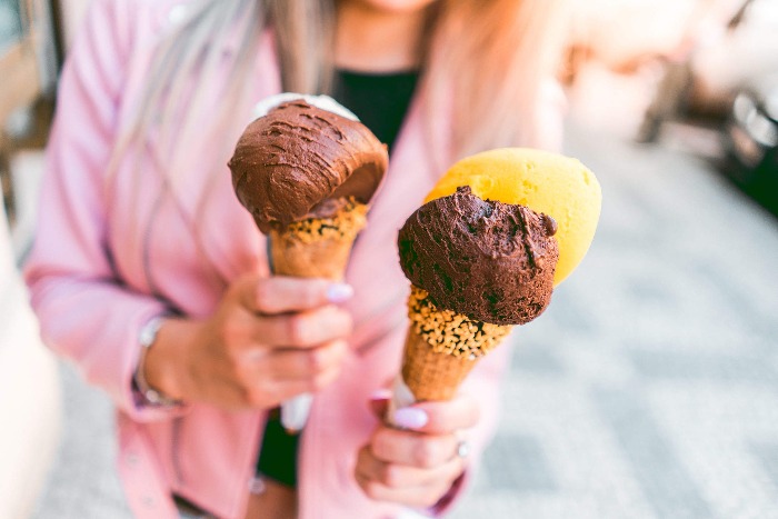 girl with a pink jacket holding three ice cream cones chocolate flavour 