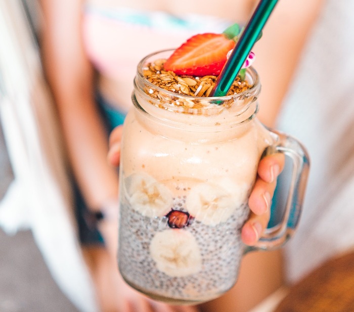 girl holding a healthy smoothie with chia nuts and a strawbetty
