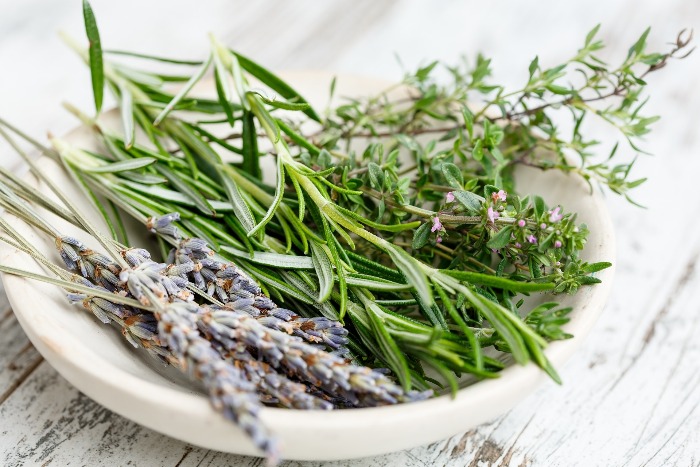 herb bouquet lavender rosemary and thyme branches in a white bowl on a wooden table