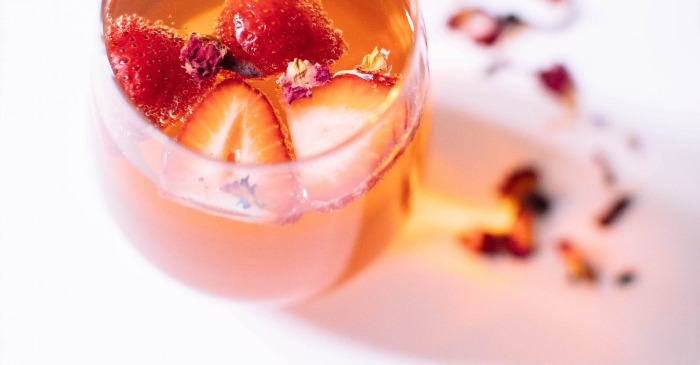 rose and strawberry ice tea in a glass on a white table