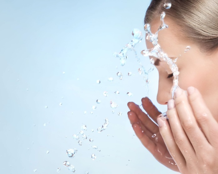 woman with blond hair splashing water on her face
