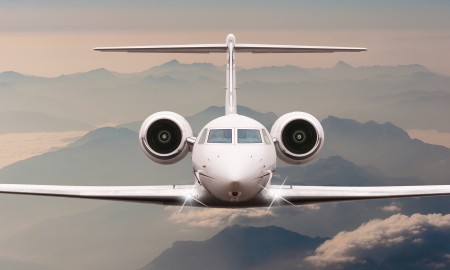 Airplane fly over clouds and Alps mountain on sunset. Front view of a big passenger or cargo aircraft, business jet, airline. Transportation and travel concept.