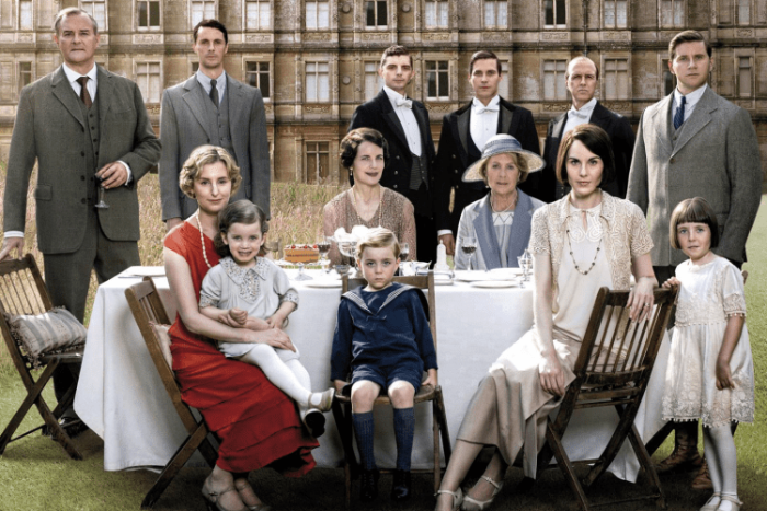 downton abbey cast in front of highcelere castle around a dining table outdoors