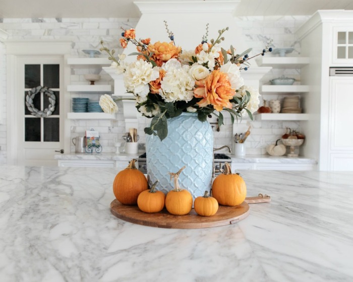 fall home decor ideas blue vase with white and orange flowers and pumpkins