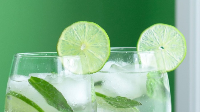 two glasses of lemongrass cocktails decorated with slices of lime