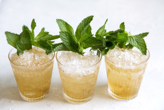 three mint julep cocktails with mint decoration with crushed iced