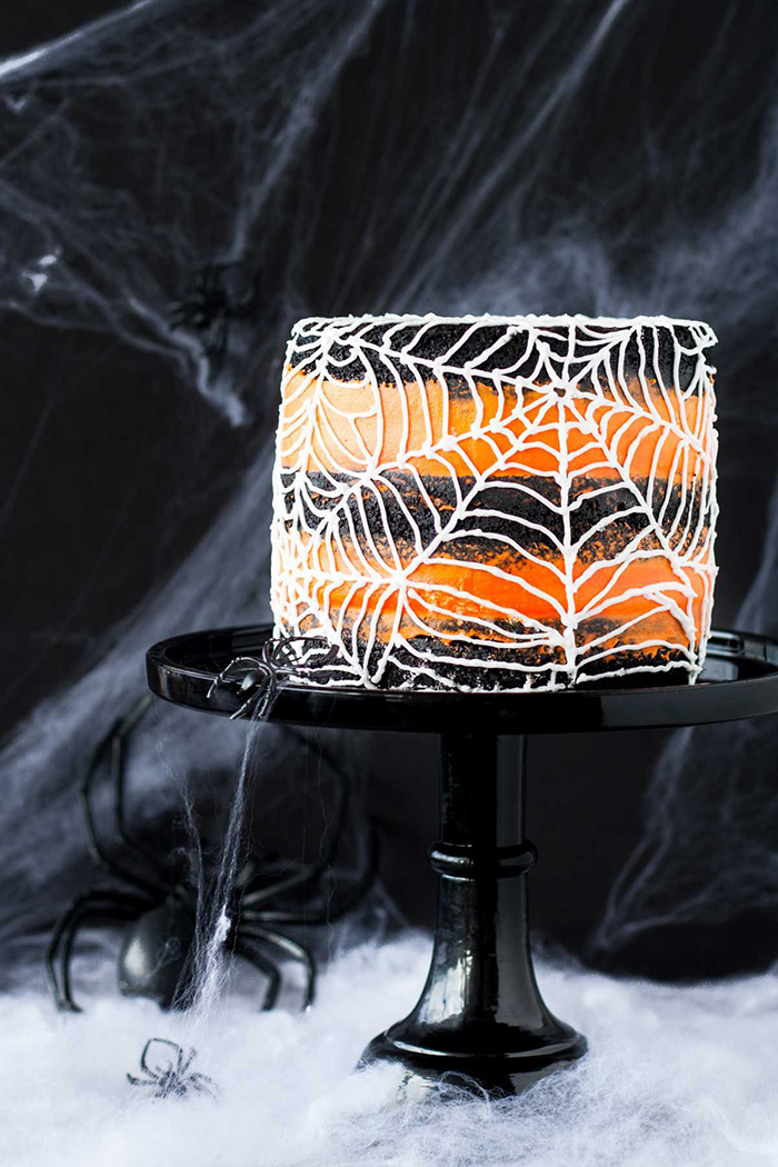 Halloween cake spider web with orange and black layers spider web in the background and a black spider