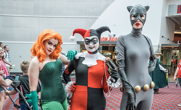 Three people in front of a cinema in Halloween costumes cat clown and a ivy woman