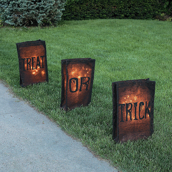 Halloween decor ideas fake outdoor fire baskets on a grass lawn with words on them