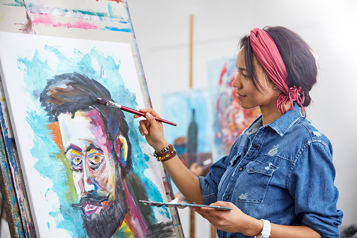 best new hobbies woman in denim jacket painting a man in different colours