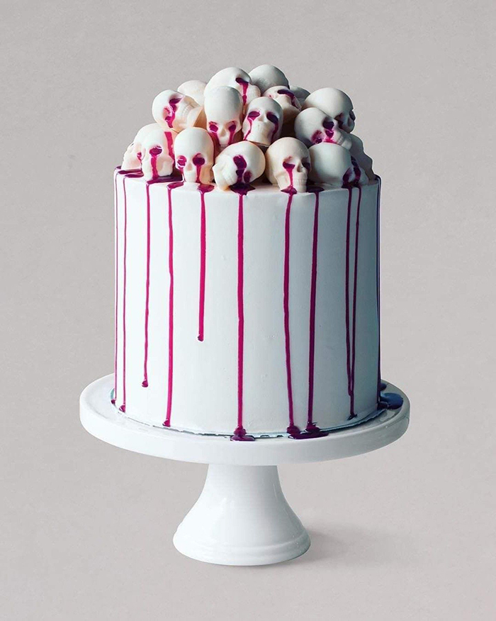 Spooky halloween white cake with skulls on top on a white plate white background