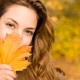 DIY Fall Wreathssmiling woman with a leave in front of her facr