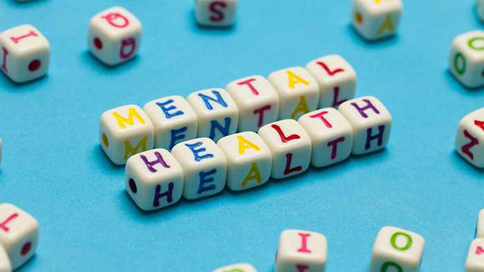 mental health cubes with colorful letters scattered on a blue background