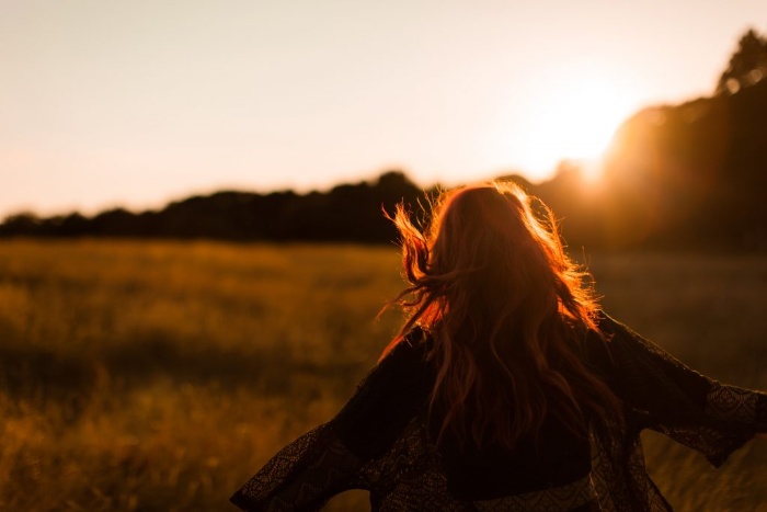 abundance mindset woman running towards the sunset with arms spread