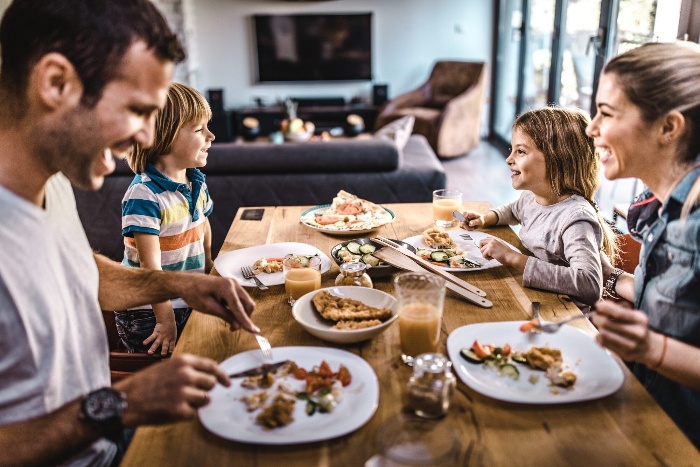 Thanksgiving celebration on a budget family of four on a dining table laughing and eating indoor activities