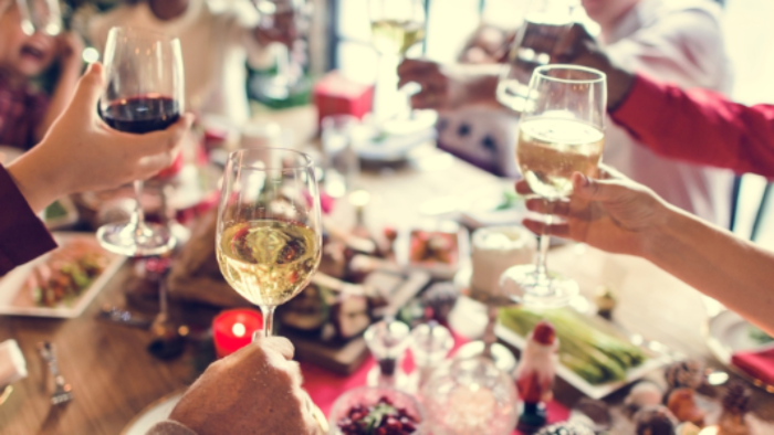 family cheering over a table with food glasses with wine in the air