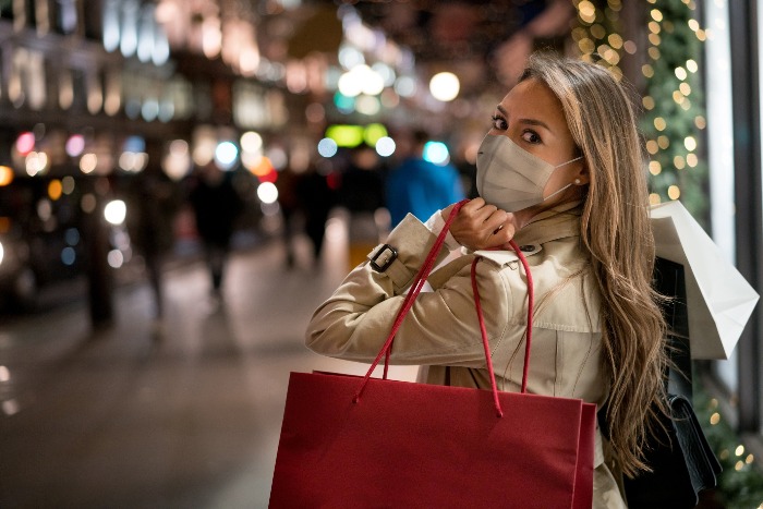 woman with a mask shopping for the holidays with a mask outdoors shopping street carrying a big read bag