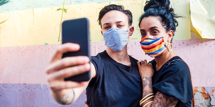 a girl and a boy with colorful masks taking a selfie in front of a wall