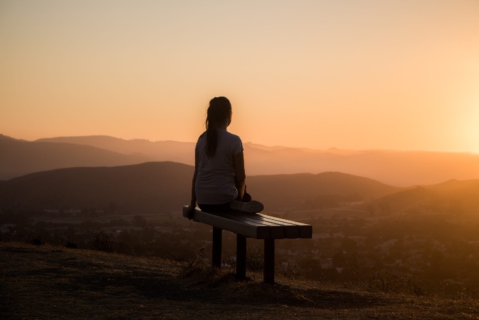 meditation for gratitude girl watching the sunset on a bench outdoors 