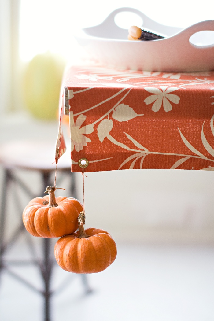 Table decorated with mini pumpkins orange table cloth in a kitchen