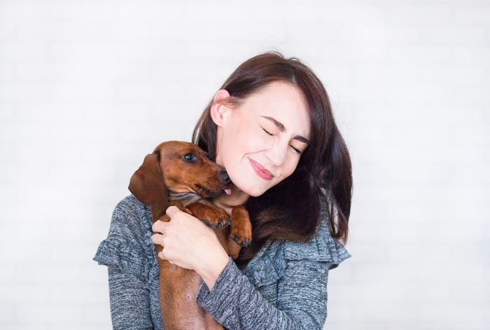 girl with dark hair cuddling a dog smiling and having fun 