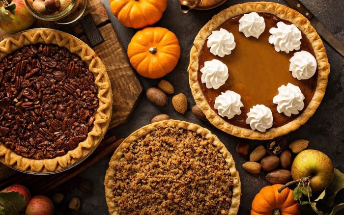 Thanksgiving treat different pumpkin pies with and without nuts with cream on a decorated table