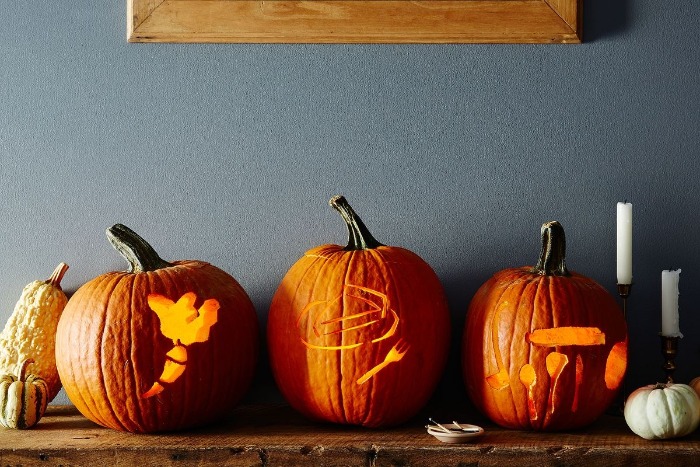 three carved pumpkins on a shelf gray wall in the background