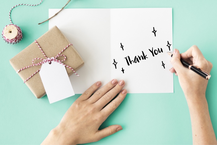 effect of gratitude person writing thank you card with a little wrapped gift