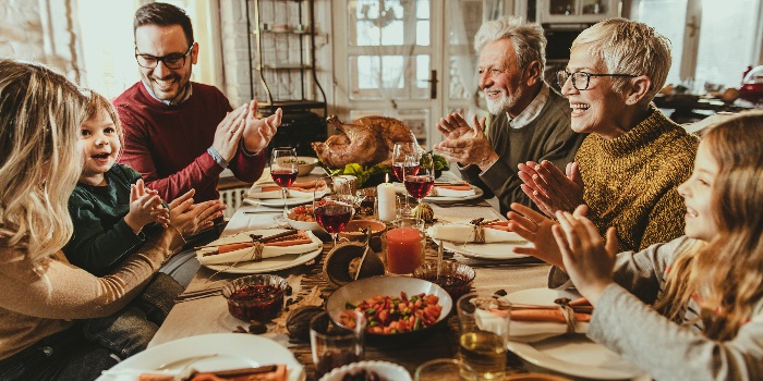 family around the table celebrating thanksgiving clapping and singing