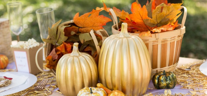 thanksgiving themed table decor with golden pumpkins and foliage outdoor table setting