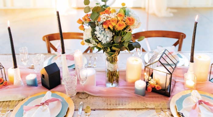 stylish wedding table with decorations in pink and light blue and tall dark candles