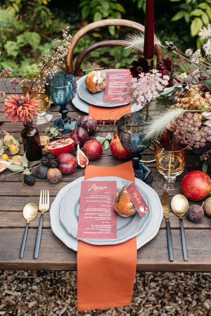 Thanksgiving themed wedding table decorated with fruits colorful glasses and flowers