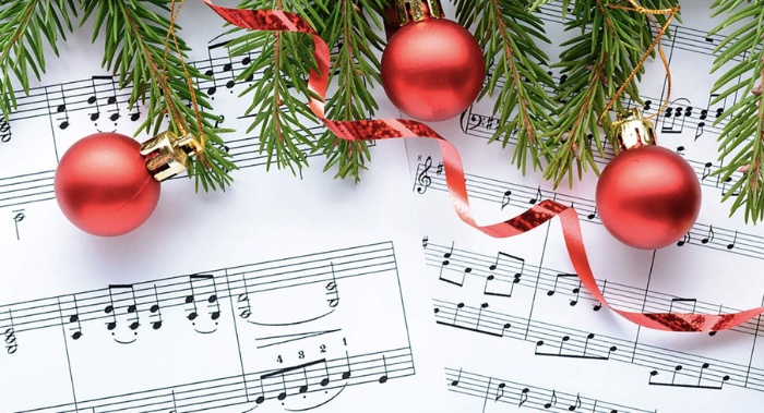 Christmas carol musical notes decorated with red baubles pine branches and a ribbon