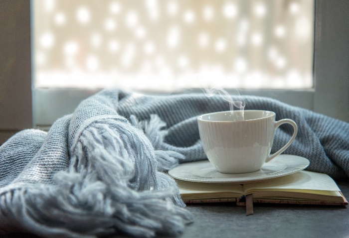 Holiday season white cup with light blue blanket in front of a window