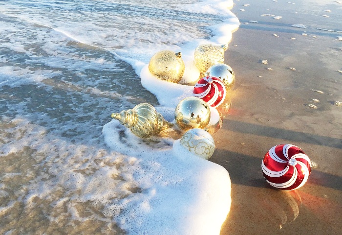 Christmas ornaments and baubles on the beach washed by the waves