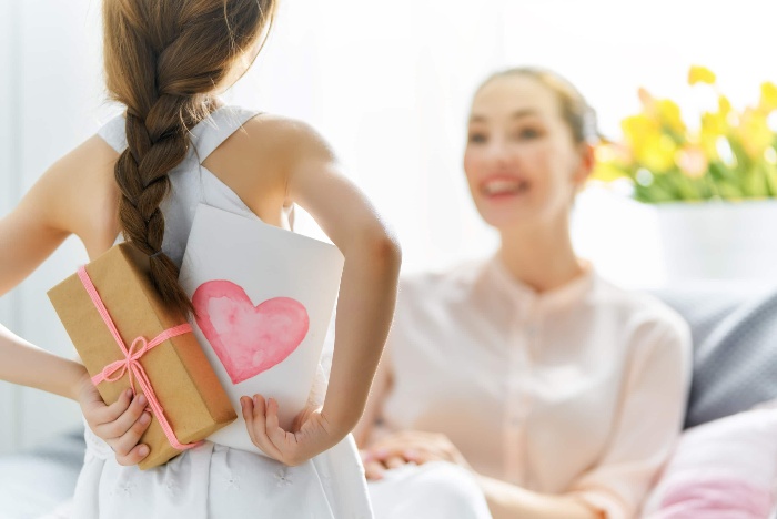 little girl holding a card and a gift for her mother