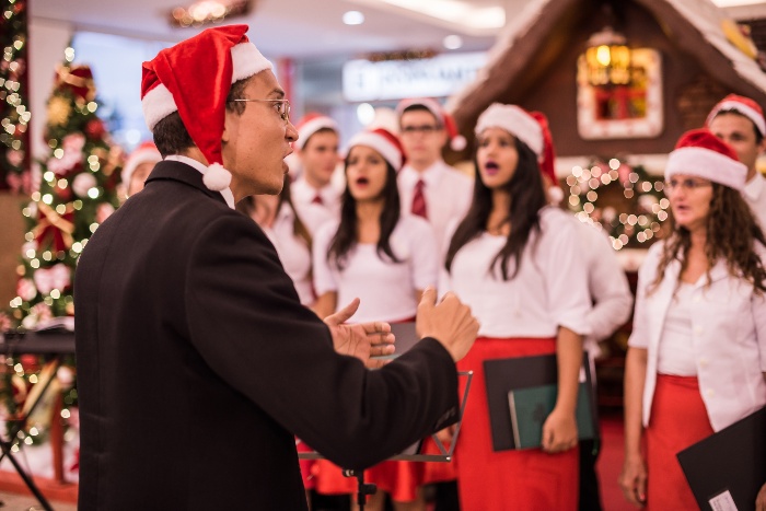 christmas choir performance singers dressed in white and red and a conductor with a red hat