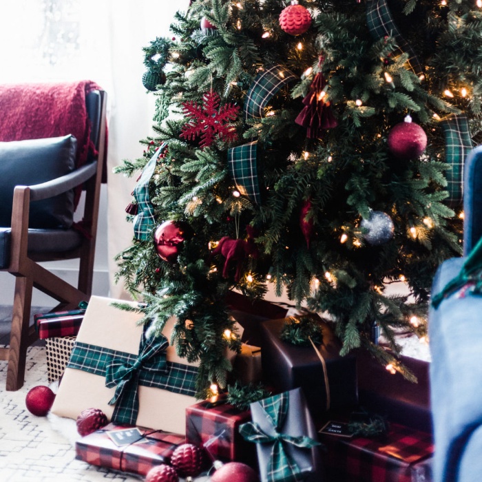 christmas decorations tree decorated in green and red with presents under it and a reading chair