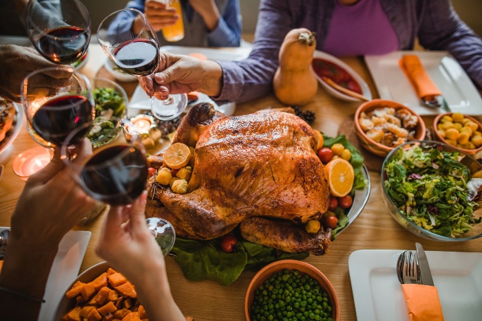 christmas dinner people eating turkey raising a toast with red wine