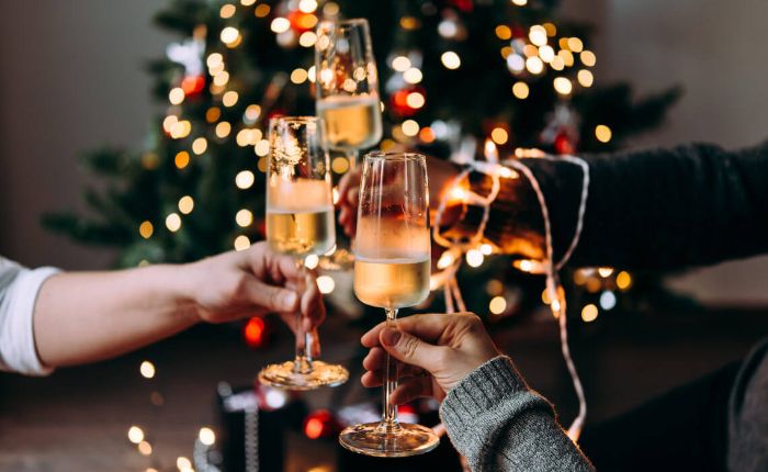 christmas toast with champagne in front of a christmas tree