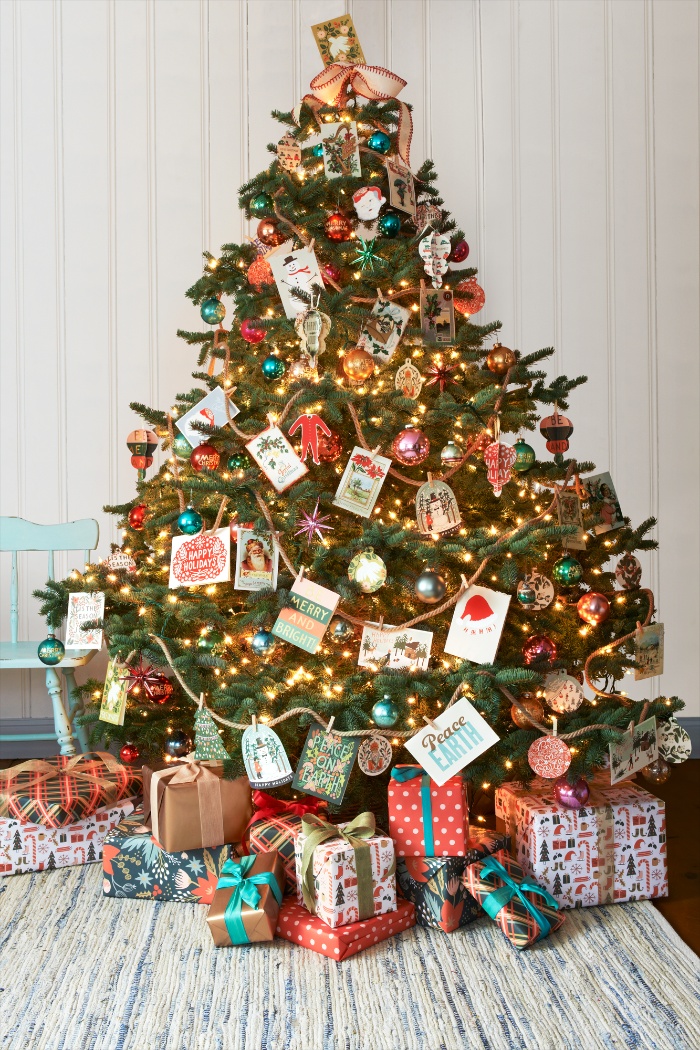 christmas tree decorated with handmade cards and lights with a lot of gifts