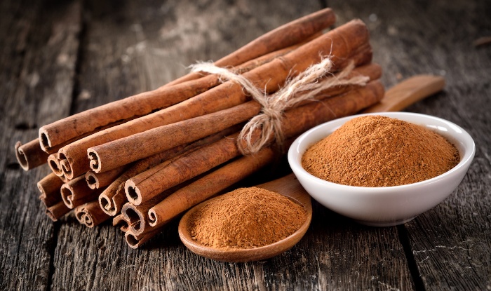 Bunch of cinnamon sticks tied together and cinnamon powder in a spoon and in a bowl