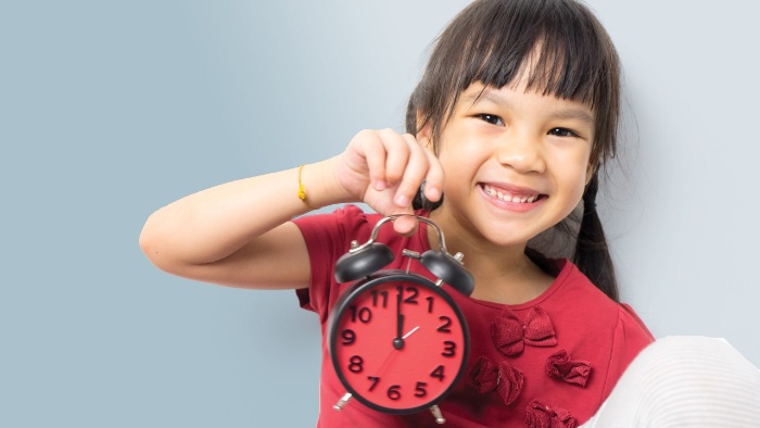 little girl with red shirt holding a red clock in her hand