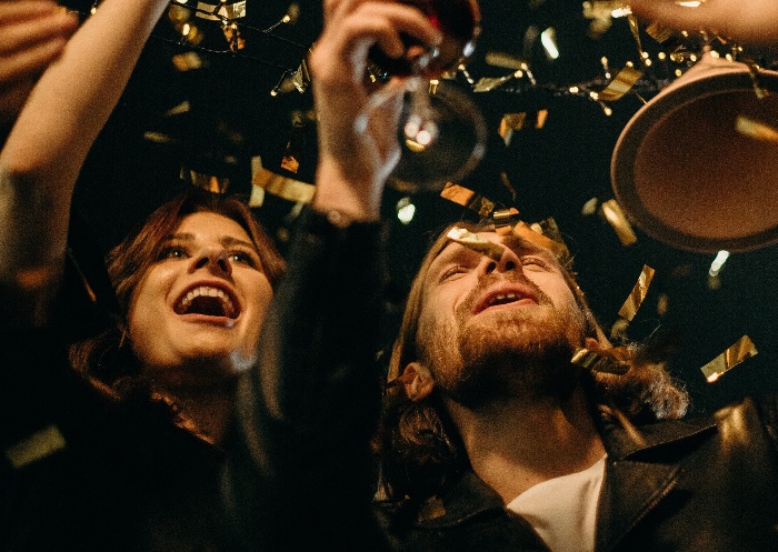 couple cheers at new year's eve party with confetti in flying in the air