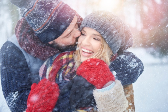 new year's eve traditions couple laughing and cuddling in the snow