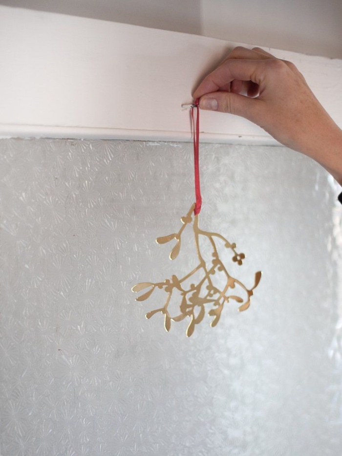 decorating with mistletoe at home woman handing an ornament on the window