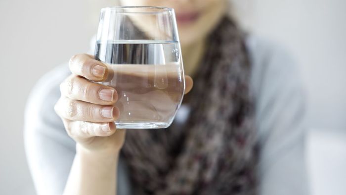 woman holding a full glass of water in her hand 