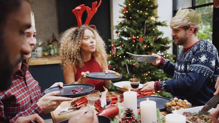 friends celebrating new year on a full table with a christmas tree woman with deer horns