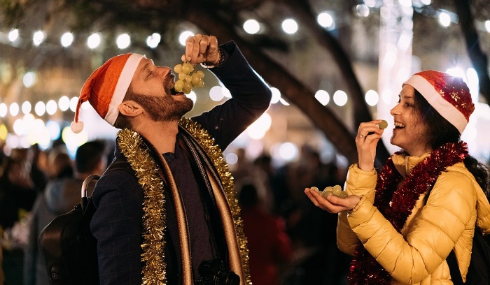 couple eating grapes together at new year's eve outdoor market 