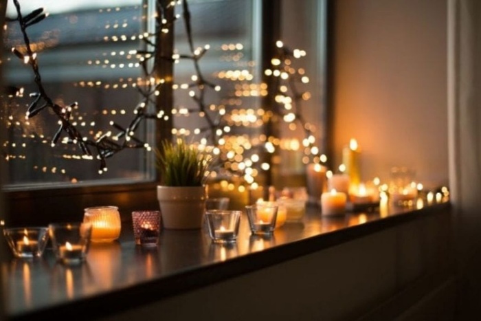 fairy lights and candles arranged on a window sill